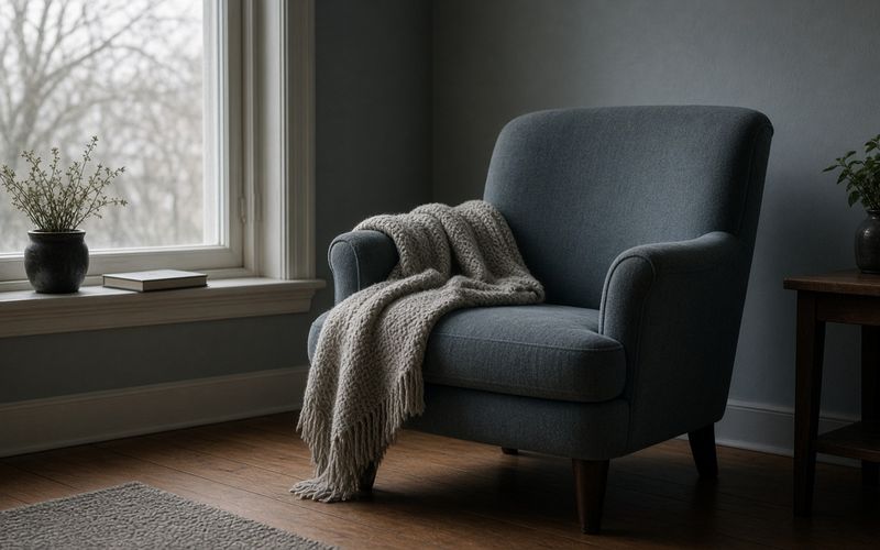 Leerer Sessel mit Decke am Fenster — Erholung im Grippeverlauf